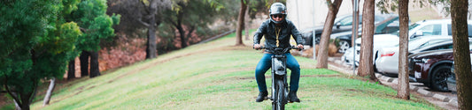A man riding electric bike on the neatly cut grass next to the parking lots, showing off his ebike accessories