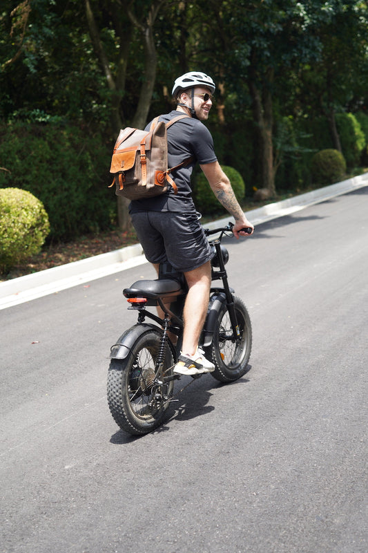Man riding black eBike on road with helmet and backpack, illustrating eBike cost analysis benefits