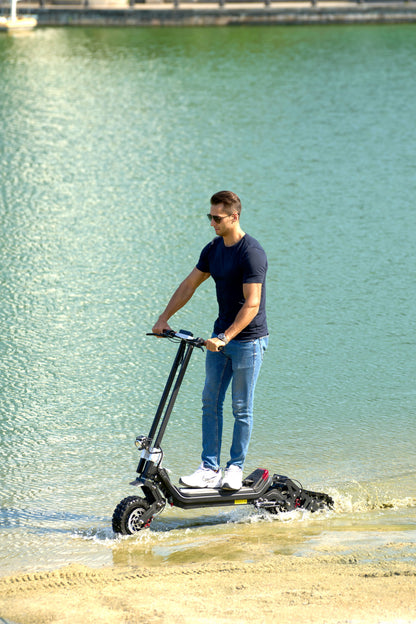 G63 Convertible Electric Scooter on water's edge with rider.